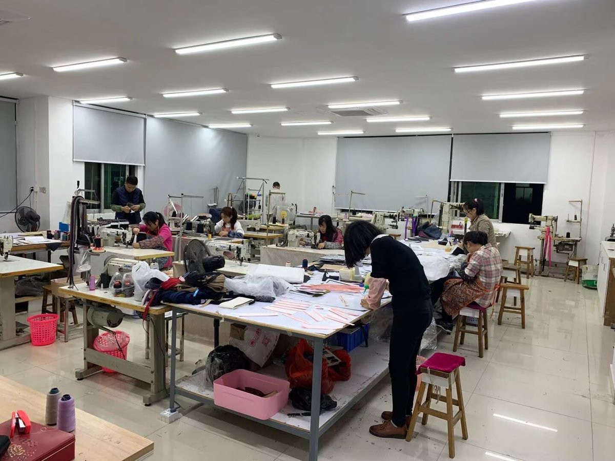 Sewing operators stitching leather jewelry box panels at worktables in the box workshop