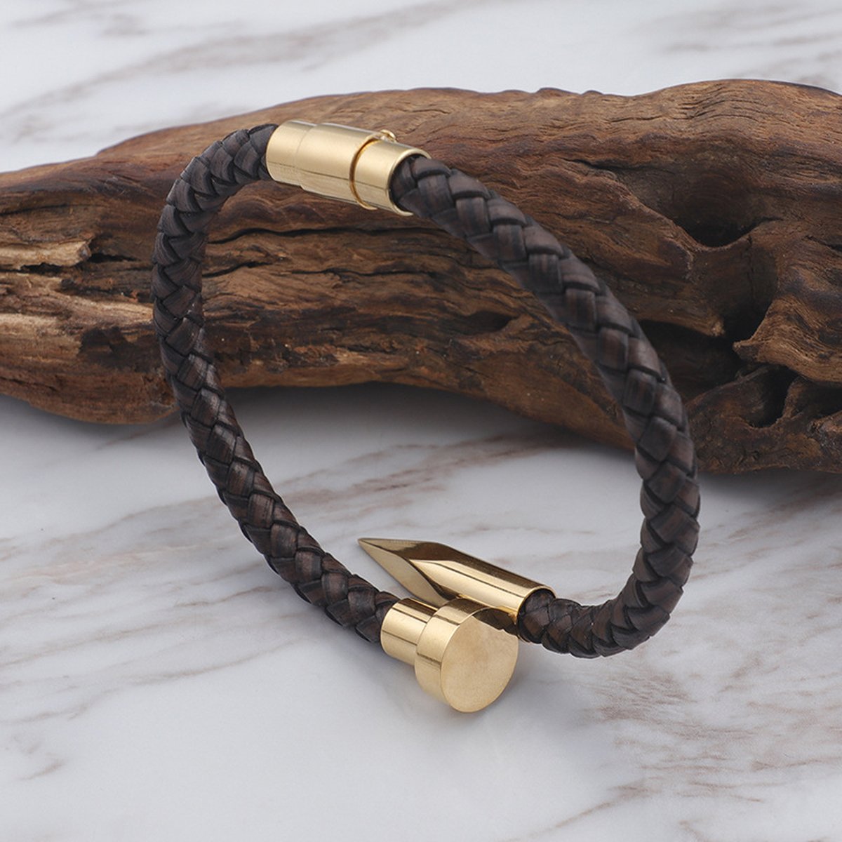 Gold nail tip braided leather bracelet displayed on rustic wood prop