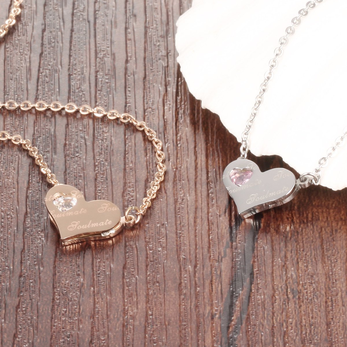 Rose gold and silver soulmate heart pendant necklaces on wooden background